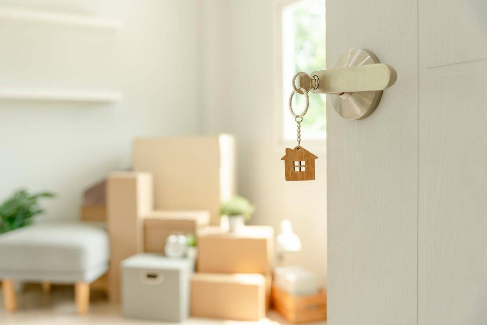 Moving house, relocation. The key was inserted into the door of the new house, inside the room was a cardboard box containing personal belongings and furniture. move in the apartment or condominium.